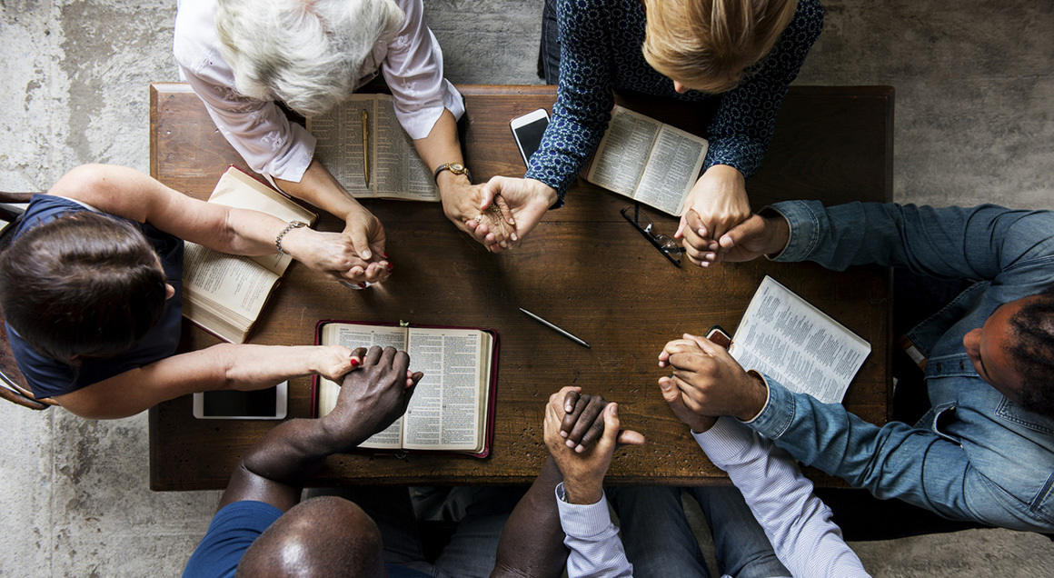 Diverse group holding hands around table