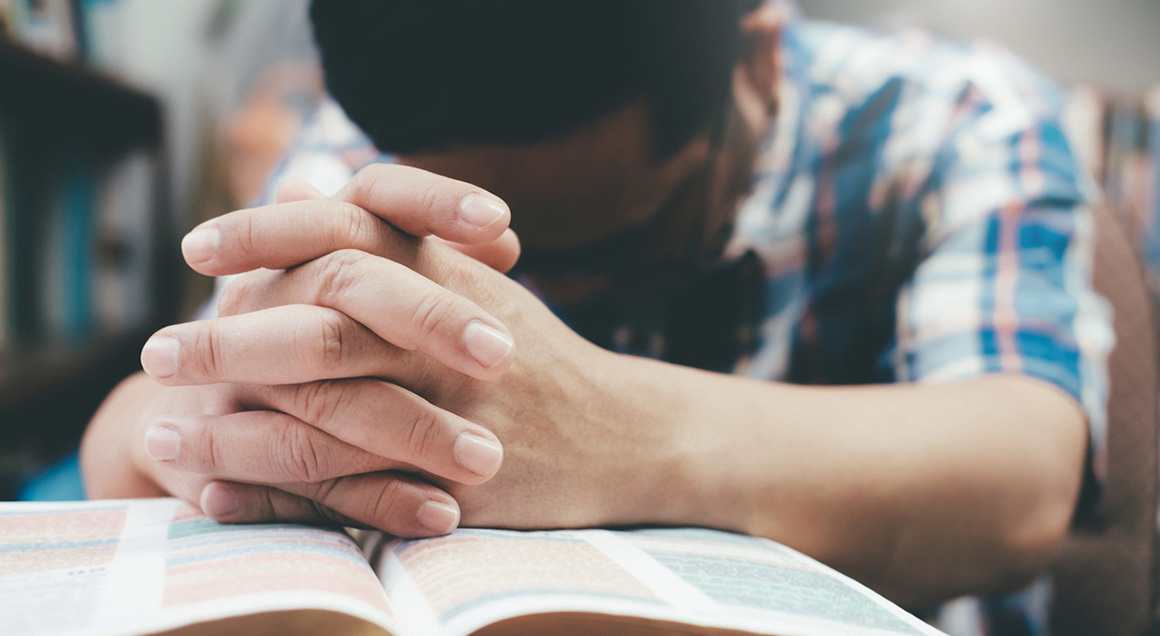 Stock hands praying over open bible 72px