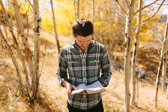 Stock man reading bible in woods