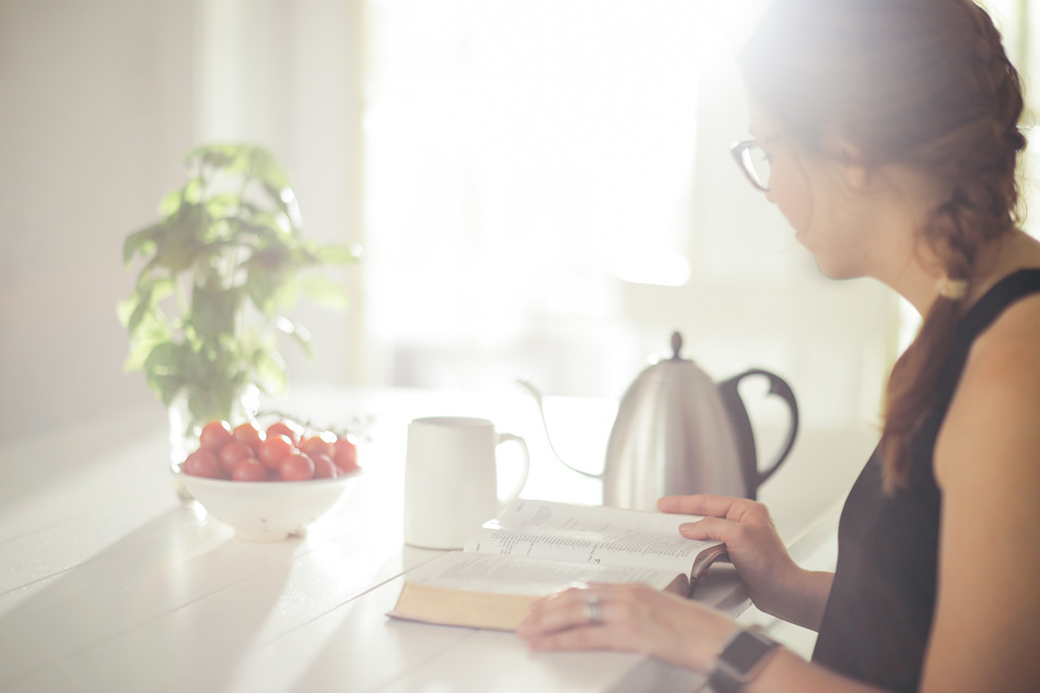 Stock woman reading bible while drinking coffee
