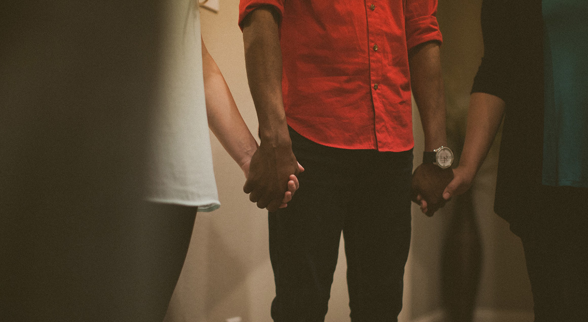Three people holding hands in prayer
